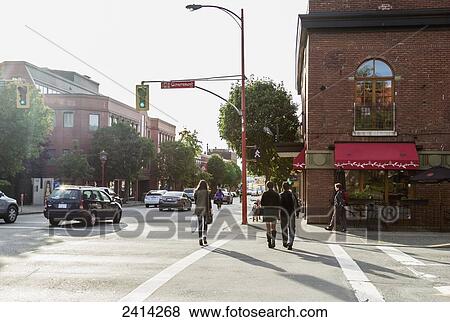 Stock Photo - A young couple crossing the street in the downtown; Victoria, Vancouver Island, British Columbia. Fotosearch