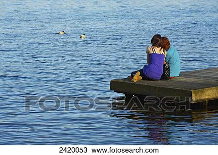 A young couple cuddles together on a wooden dock along the river; Hamburg, Germany View Large Photo Image Stock Image - A young couple cuddles together on a wooden dock along the river; Hamburg, Germany. Fotosearch