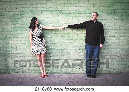 Stock Image - A Young Couple Holding Hands At Orange Circle Antique Mall; Orange California Usa. Fotosearch