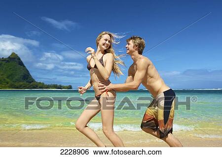 Stock Photograph - A young couple playing on the beach; Wailua, Hawaii, United States of America. Fotosearch