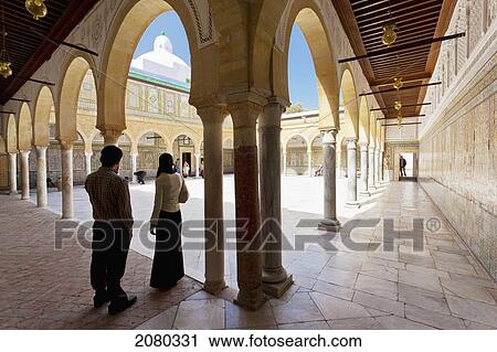 Stock Image - A Young Couple Stand On The Threshold Of The First Court Inside The Barber's Mosque; Kairouan, Tunisia, North Africa. Fotosearch