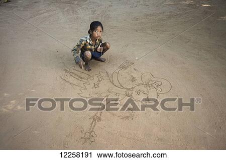 Stock Image - A young girl drawing on the ground for asking money from tourists, Preah Khan Temple from Angkor; Siem Reap, Cambodia. Fotosearch