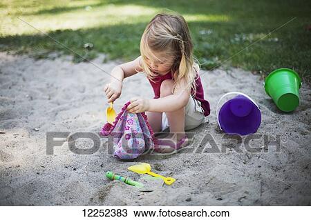 Stock Image - A young girl plays in the sand; Surrey, British Columbia, Canada. Fotosearch