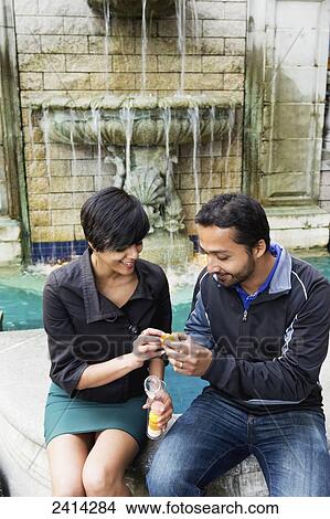 A young Indian ethnicity couple snacking by a fountain; Victoria, Vancouver Island, British Columbia View Large Photo Image Picture - A young Indian ethnicity couple snacking by a fountain; Victoria, Vancouver Island, British Columbia. Fotosearch