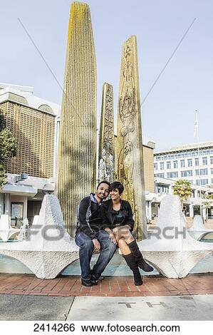 A young Indian ethnicity couple posing at the Ceramic Fins of Centennial Square fountain; Victoria, Vancouver Island, British Columbia View Large Photo Image Stock Photograph - A young Indian ethnicity couple posing at the Ceramic Fins of Centennial Square fountain; Victoria, Vancouver Island, British Columbia. Fotosearch