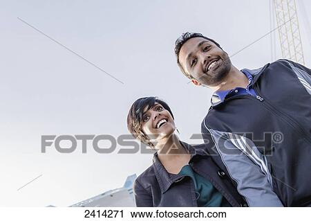 Stock Image - A young Indian ethnicity couple walking together smiling and laughing; Victoria, Vancouver Island, British Columbia. Fotosearch