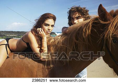 Stock Image - A young man and woman with a horse on the beach; Hawaii, United States of America. Fotosearch