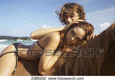 Stock Image - A young man and woman with a horse on the beach; Hawaii, United States of America. Fotosearch