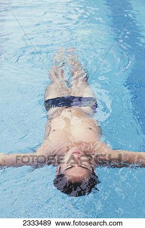 Stock Photo - A young man floating on his back in a swimming pool; Honolulu, Oahu, Hawaii, United States of America. Fotosearch