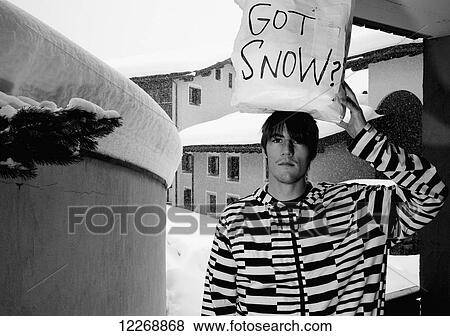 Stock Photo - A young man holds a handwritten sign asking got snow?; St. Mortitz, Switzerland. Fotosearch