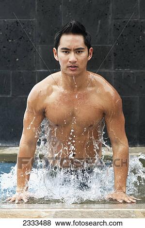 A young man jumping up out of a swimming pool with water splashing; Honolulu, Oahu, Hawaii, United States of America View Large Photo Image Stock Photo - A young man jumping up out of a swimming pool with water splashing; Honolulu, Oahu, Hawaii, United States of America. Fotosearch