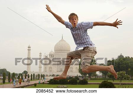 Stock Image - A Young Man Leaps In The Air With The Taj Mahal In The Background; Agra Uttar Pradesh India. Fotosearch