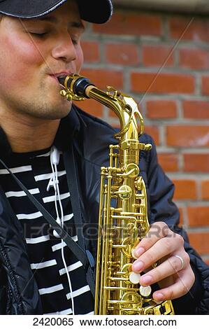 Stock Photography - A young man playing a saxophone; Hamburg, Germany. Fotosearch