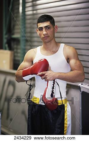 Stock Photo - A young man putting on boxing gloves; San Francisco, California, USA. Fotosearch