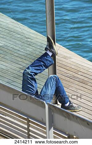A young man relaxed on a wooden promenade at the water's edge; Barcelona, Spain View Large Photo Image Stock Image - A young man relaxed on a wooden promenade at the water's edge; Barcelona, Spain. Fotosearch