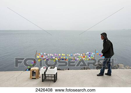 Stock Photo - A young man sets up a shooting target at the water's edge; Istanbul, Turkey. Fotosearch