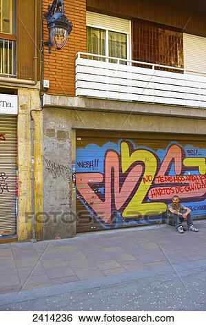 A young man sits outside a residential building with graffiti on the garage doors; Barcelona, Spain View Large Photo Image Stock Photograph - A young man sits outside a residential building with graffiti on the garage doors; Barcelona, Spain. Fotosearch