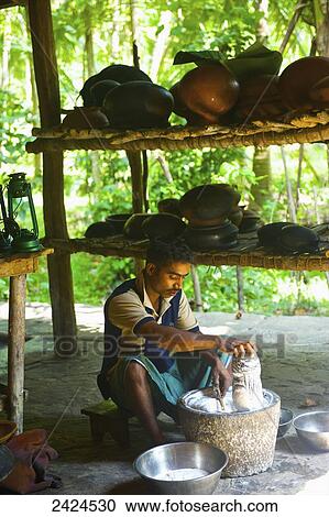 Stock Image - A young man sits working in a kitchen; Ulpotha, Embogama, Sri Lanka. Fotosearch