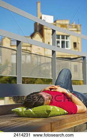 A young man snoozing on a bench in an urban area; Barcelona, Spain View Large Photo Image Stock Image - A young man snoozing on a bench in an urban area; Barcelona, Spain. Fotosearch