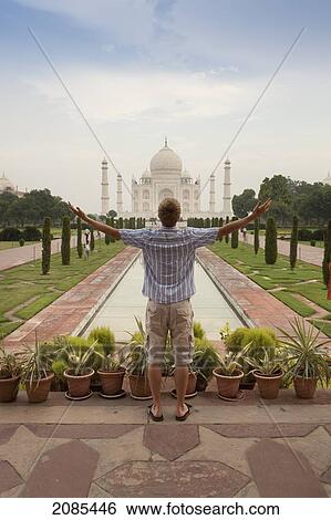 Stock Photograph - A Young Man With Arms Outstretched As He Looks At The Tah Mahal; Agra Uttar Pradesh India. Fotosearch
