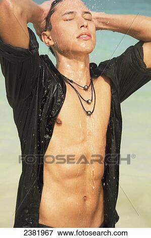 A young man with open shirt stands in splashing water; Honolulu, Oahu, Hawaii, United States of America View Large Photo Image Stock Photo - A young man with open shirt stands in splashing water; Honolulu, Oahu, Hawaii, United States of America. Fotosearch