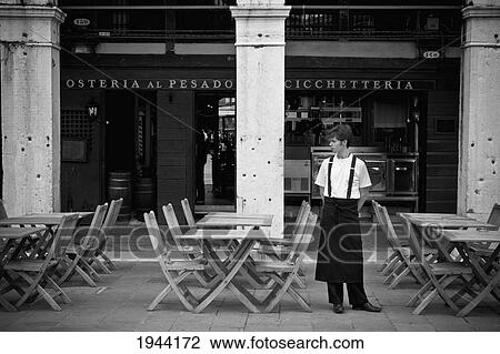 A Young Server Stands By The Tables On The Patio Outside A Restaurant; Venice Venezia Italy View Large Photo Image Stock Image - A Young Server Stands By The Tables On The Patio Outside A Restaurant; Venice Venezia Italy. Fotosearch