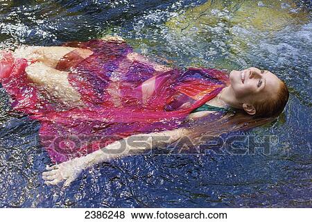 A young woman floating in the water wearing a red swimsuit coverup; Hawaii, United States of America View Large Photo Image Stock Photo - A young woman floating in the water wearing a red swimsuit coverup; Hawaii, United States of America. Fotosearch