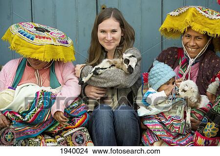 Picture - A Young Woman Holds A Goat And Sits Between Two Peruvian Women; Cusco Peru. Fotosearch