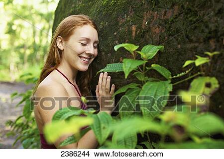 Picture - A young woman hugs a tree; Hawaii, United States of America. Fotosearch