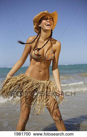 A young woman in a bikini and grass skirt on the beach at the water's edge; Oahu, Hawaii, United States of America View Large Photo Image Stock Image - A young woman in a bikini and grass skirt on the beach at the water's edge; Oahu, Hawaii, United States of America. Fotosearch