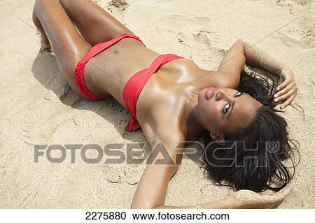 A young woman in a red bikini lays on a sandy beach; Maui, Hawaii, United States of America View Large Photo Image Stock Image - A young woman in a red bikini lays on a sandy beach; Maui, Hawaii, United States of America. Fotosearch