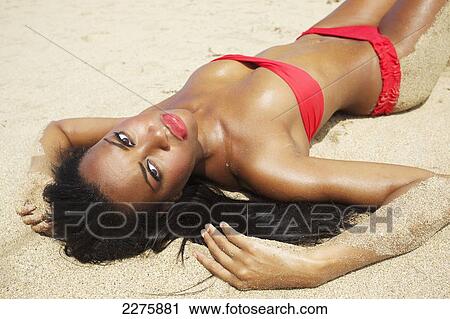 A young woman in a red bikini lays on a sandy beach; Maui, Hawaii, United States of America View Large Photo Image Stock Image - A young woman in a red bikini lays on a sandy beach; Maui, Hawaii, United States of America. Fotosearch