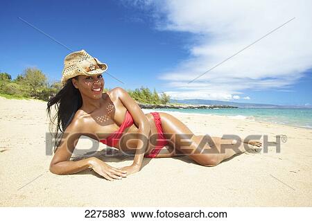 A young woman in a red bikini lays on a sandy beach; Maui, Hawaii, United States of America View Large Photo Image Stock Image - A young woman in a red bikini lays on a sandy beach; Maui, Hawaii, United States of America. Fotosearch