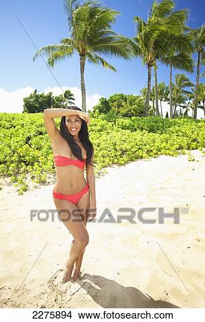 A young woman in a red bikini posing on the beach of an hawaiian island; Maui, Hawaii, United States of America View Large Photo Image Picture - A young woman in a red bikini posing on the beach of an hawaiian island; Maui, Hawaii, United States of America. Fotosearch