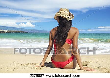 A young woman in a red bikini sitting on the beach of an hawaiian island; Maui, Hawaii, United States of America View Large Photo Image Stock Photo - A young woman in a red bikini sitting on the beach of an hawaiian island; Maui, Hawaii, United States of America. Fotosearch