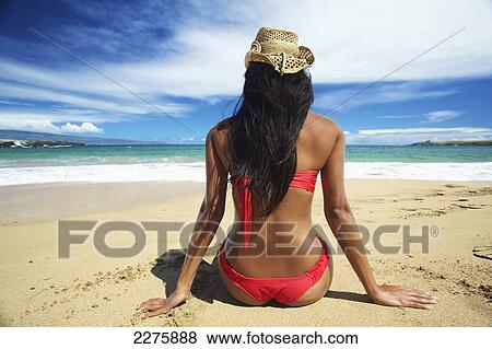A young woman in a red bikini sitting on the beach of an hawaiian island; Maui, Hawaii, United States of America View Large Photo Image Stock Photo - A young woman in a red bikini sitting on the beach of an hawaiian island; Maui, Hawaii, United States of America. Fotosearch