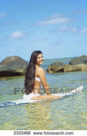 A young woman in a strapless bikini sitting on a surfboard; Kauai, Hawaii, United States of America View Large Photo Image Stock Photo - A young woman in a strapless bikini sitting on a surfboard; Kauai, Hawaii, United States of America. Fotosearch