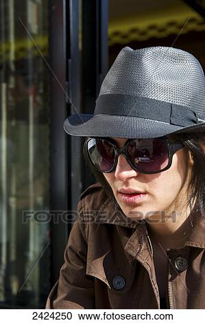 Stock Image - A young woman in a stylish hat and sunglasses, Marais district; Paris, France. Fotosearch