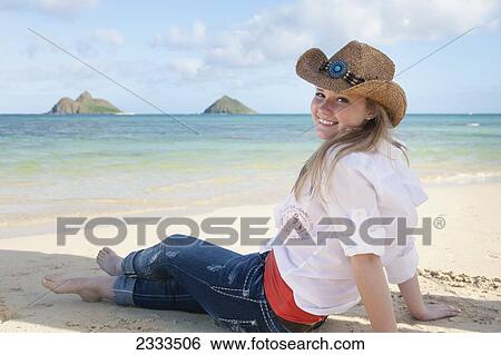 A young woman in a western style hat sitting on the beach; Honolulu, Oahu, Hawaii, United States of America View Large Photo Image Stock Photograph - A young woman in a western style hat sitting on the beach; Honolulu, Oahu, Hawaii, United States of America. Fotosearch