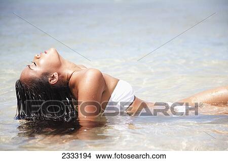 A young woman in a white bikini poses in the water; Oahu, Hawaii, United States of America View Large Photo Image Picture - A young woman in a white bikini poses in the water; Oahu, Hawaii, United States of America. Fotosearch