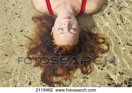 A young woman lays in the shallow water; Wailua, Hawaii, United States of America View Large Photo Image Stock Image - A young woman lays in the shallow water; Wailua, Hawaii, United States of America. Fotosearch