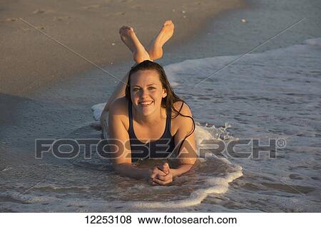 A young woman lays in the water at the beach; Nokomis, Florida, United States of America View Large Photo Image Stock Photo - A young woman lays in the water at the beach; Nokomis, Florida, United States of America. Fotosearch