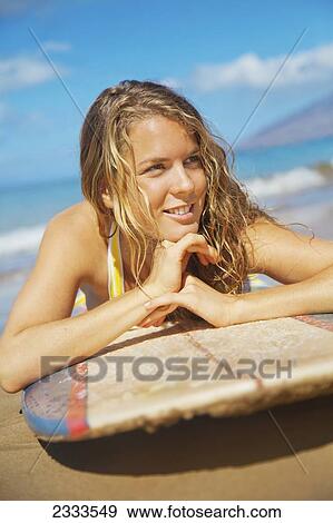 A Young Woman Lays On A Surfboard On The Sand; Maui, Hawaii, United States Of America View Large Photo Image Stock Photo - A Young Woman Lays On A Surfboard On The Sand; Maui, Hawaii, United States Of America. Fotosearch