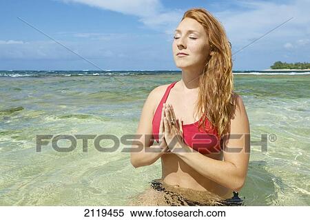 A young woman meditates in the shallow water off the coast; Wailua, Hawaii, United States of America View Large Photo Image Stock Photography - A young woman meditates in the shallow water off the coast; Wailua, Hawaii, United States of America. Fotosearch