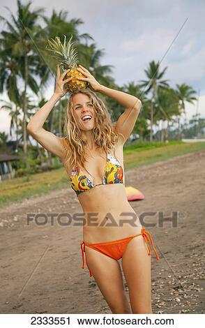 A Young Woman On The Beach In A Bikini Holding A Pineapple On Her Head; Maui, Hawaii, United States Of America View Large Photo Image Stock Image - A Young Woman On The Beach In A Bikini Holding A Pineapple On Her Head; Maui, Hawaii, United States Of America. Fotosearch