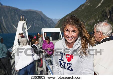 Stock Image - A Young Woman Poses With An I Love New Zealand Sweatshirt On A Boat Cruise In Milford Sound; New Zealand. Fotosearch