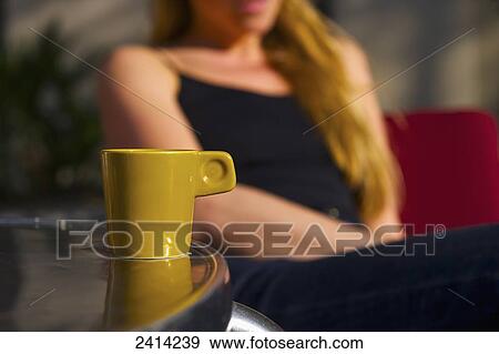 A young woman sits at an outdoor cafe with a coffee cup on the table; Barcelona, Spain View Large Photo Image Stock Photo - A young woman sits at an outdoor cafe with a coffee cup on the table; Barcelona, Spain. Fotosearch