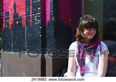 A young woman sits on a bench beside a colourful mural painted on the exterior wall of a building; Hamburg, Germany View Large Photo Image Stock Image - A young woman sits on a bench beside a colourful mural painted on the exterior wall of a building; Hamburg, Germany. Fotosearch