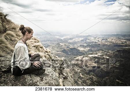 A young woman sits on a ridge overlooking the spectacular Simien mountains; Ethiopia View Large Photo Image Stock Photo - A young woman sits on a ridge overlooking the spectacular Simien mountains; Ethiopia. Fotosearch