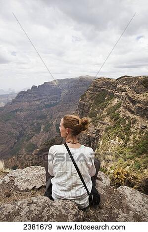 A young woman sits on a ridge overlooking the spectacular Simien mountains; Ethiopia View Large Photo Image Stock Photo - A young woman sits on a ridge overlooking the spectacular Simien mountains; Ethiopia. Fotosearch